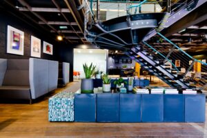 Area lounge con piante da interno, scale in metallo e arredamento moderno